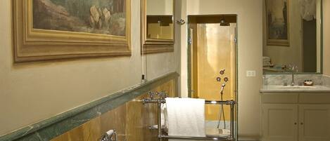 A bathroom with a freestanding bathtub, a large mirror, and a chandelier.