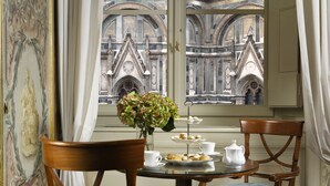 A dining table with a vase of flowers, a tray of pastries, and a teapot. - Palazzo Niccolini al Duomo (Florence)