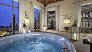 A hot tub in a room with large windows, decorative lighting, and framed pictures on the walls. - Palazzo Niccolini al Duomo (Florence)