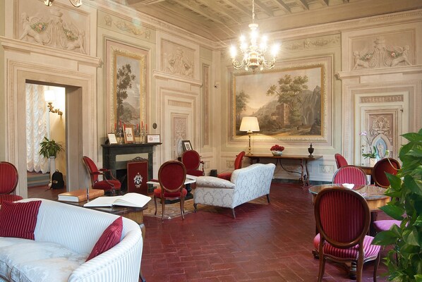 Una habitación amplia con decoraciones ornamentales en las paredes, una chimenea y cómodos asientos.