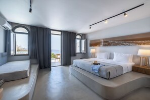 A modern hotel room with a large bed, a seating area, and a view of the outdoors.