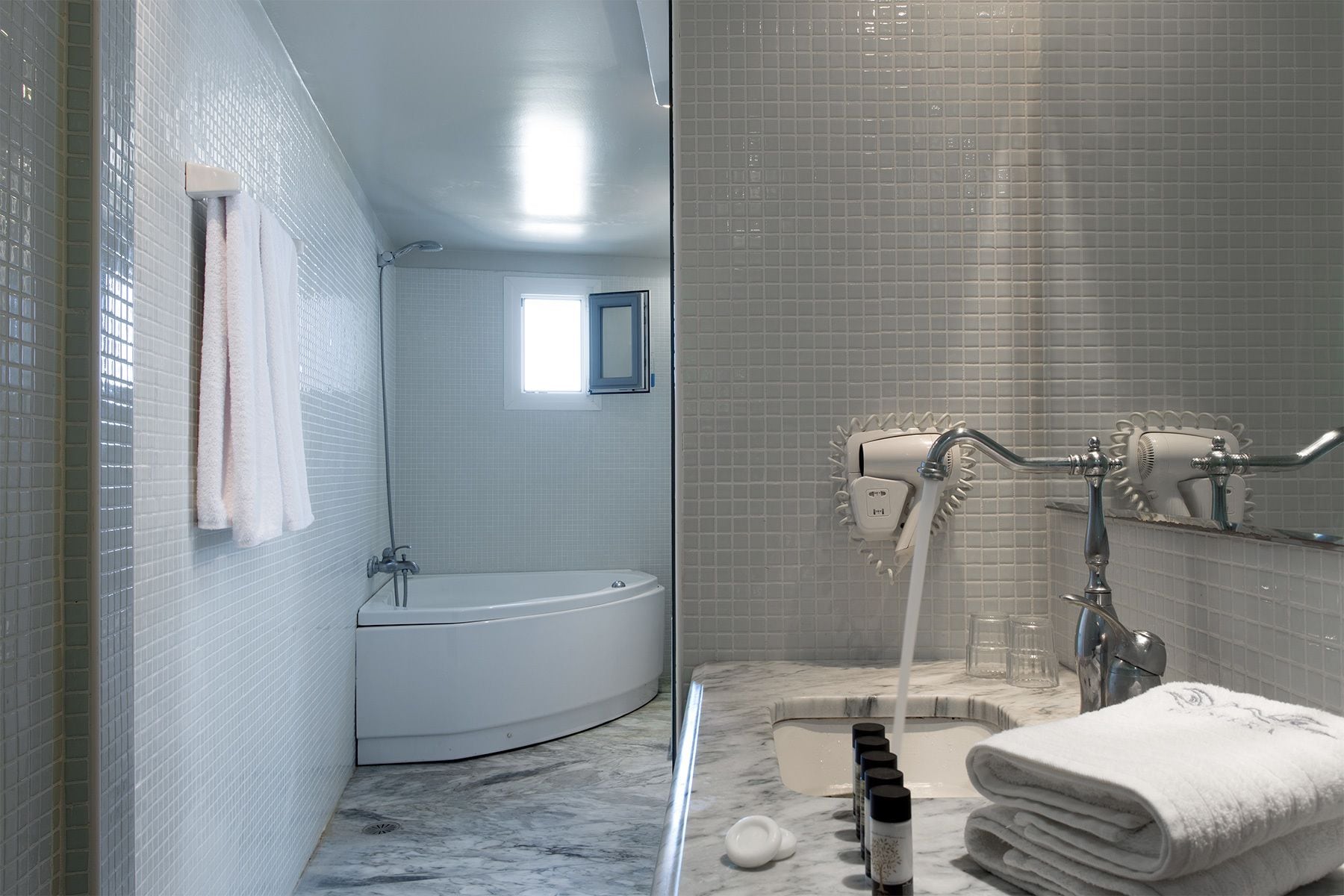 A modern bathroom with a bathtub, a shower with a rain showerhead, and a marble countertop.