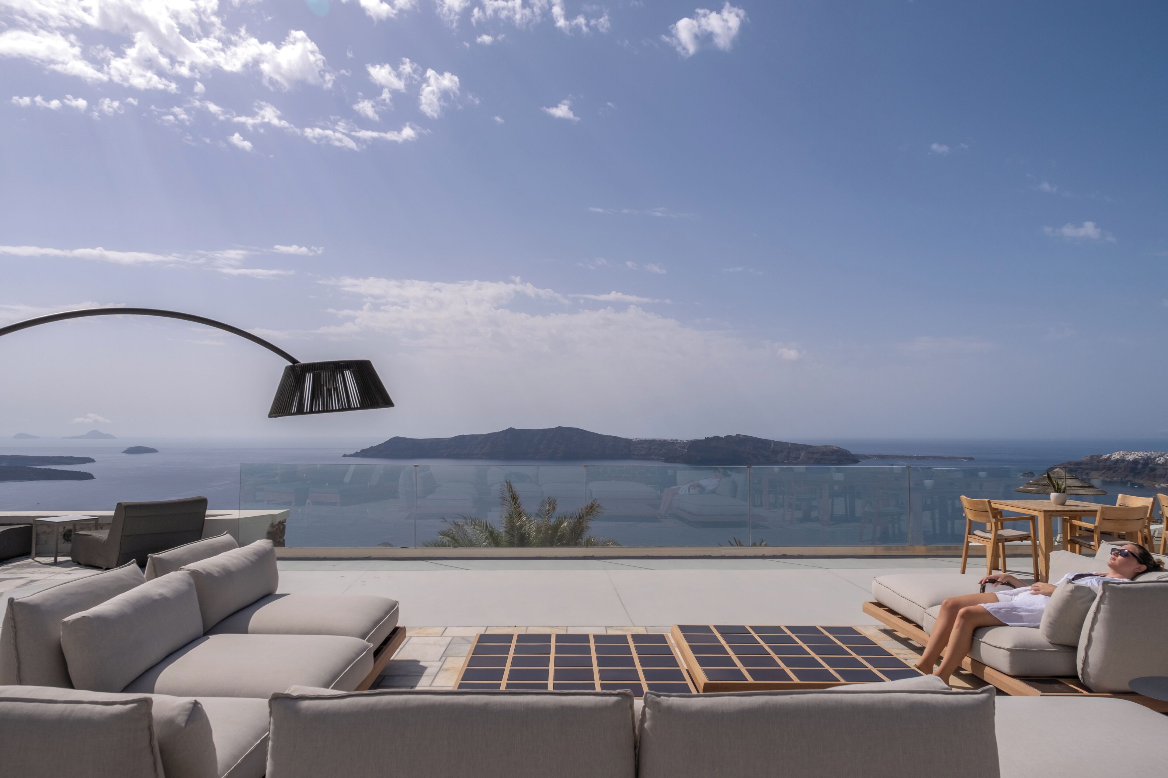 Une terrasse sur le toit offrant une vue sur la mer et les îles au loin, aménagée avec des canapés et une table.