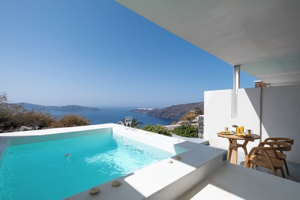 A modern outdoor pool with a clear view of the sea and distant islands.