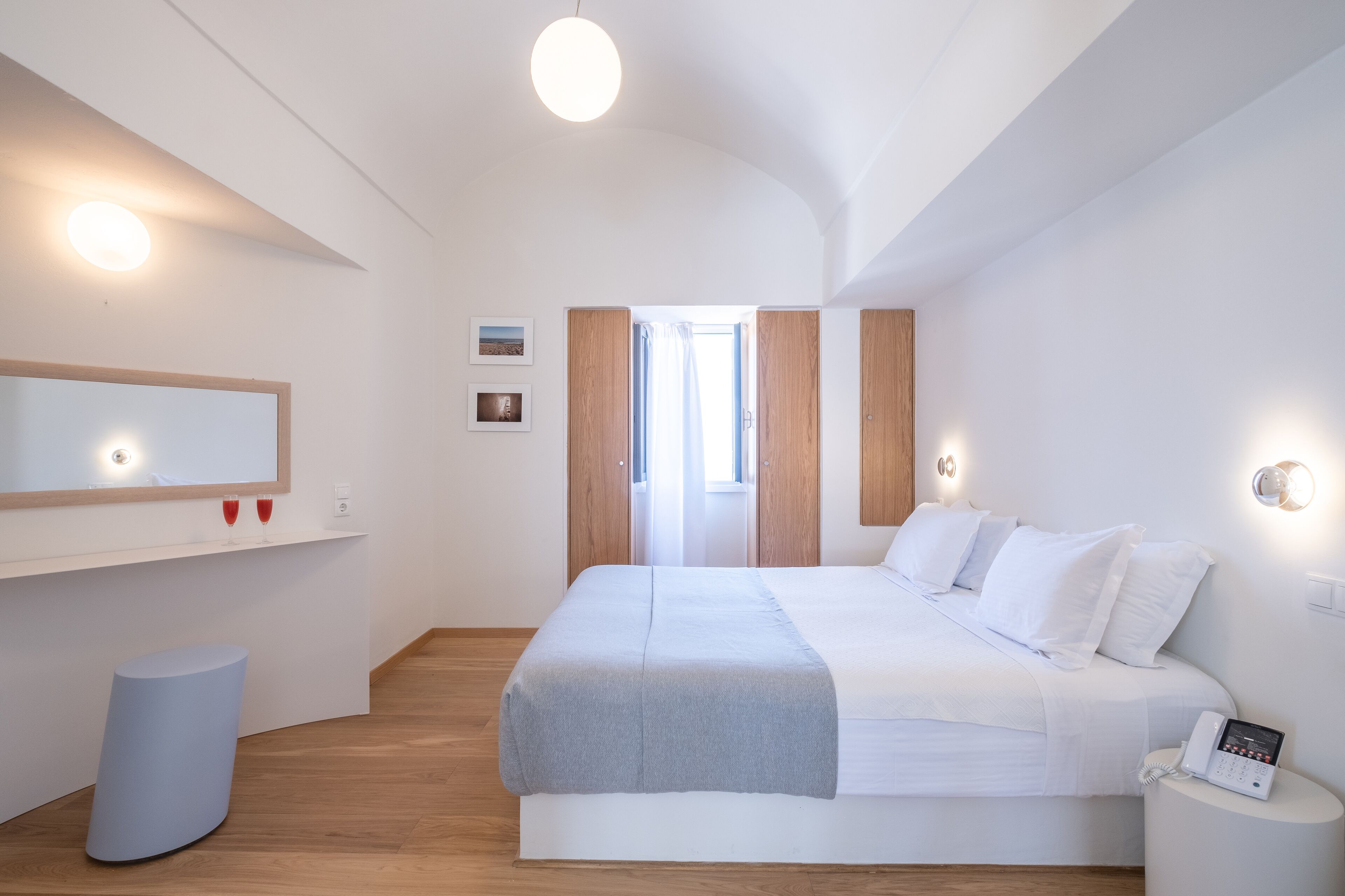 A modern bedroom with a large bed, bedside table, and a mirror.