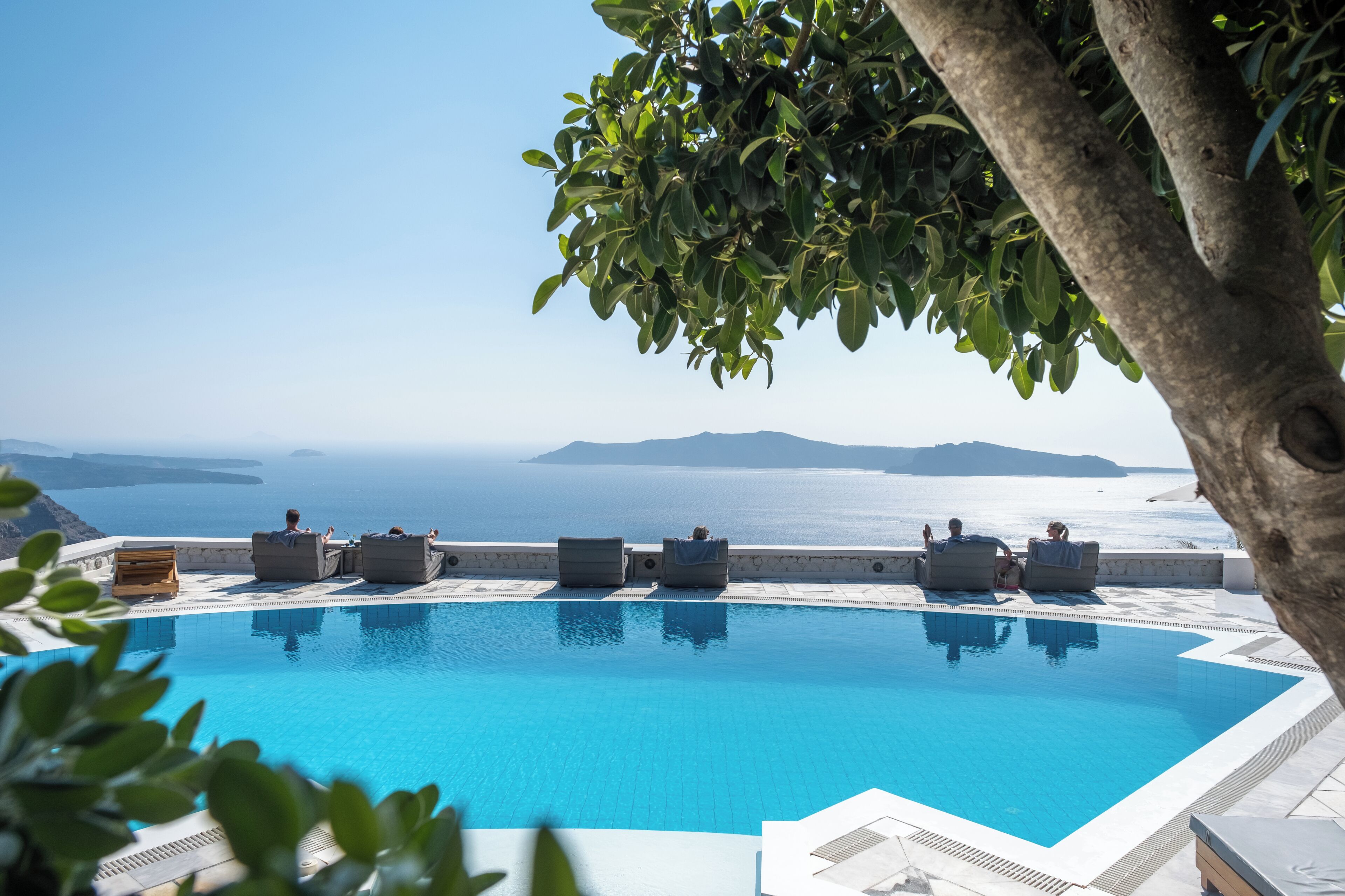 A pool with lounge chairs and a view of the sea.