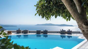 A pool with lounge chairs and a view of the sea.