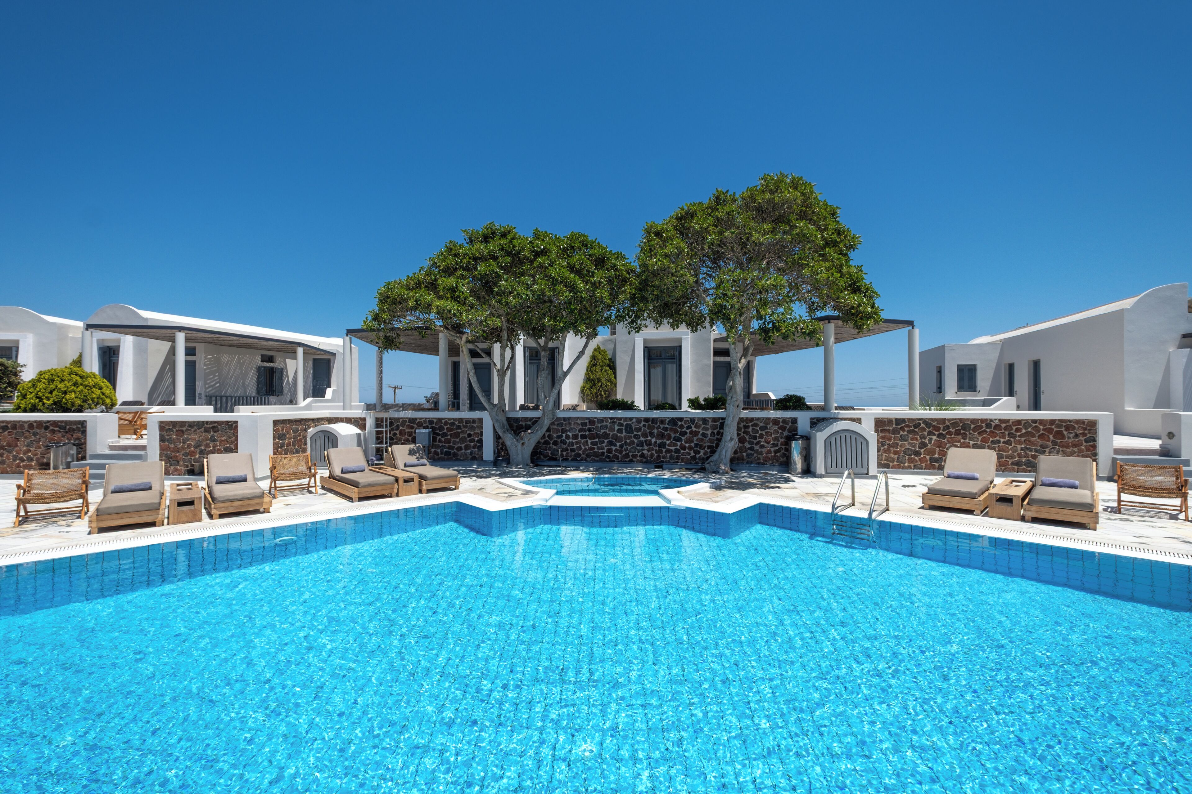 A swimming pool with lounge chairs and a pergola with trees.