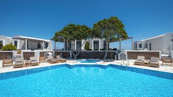 A swimming pool with lounge chairs and a pergola with trees.