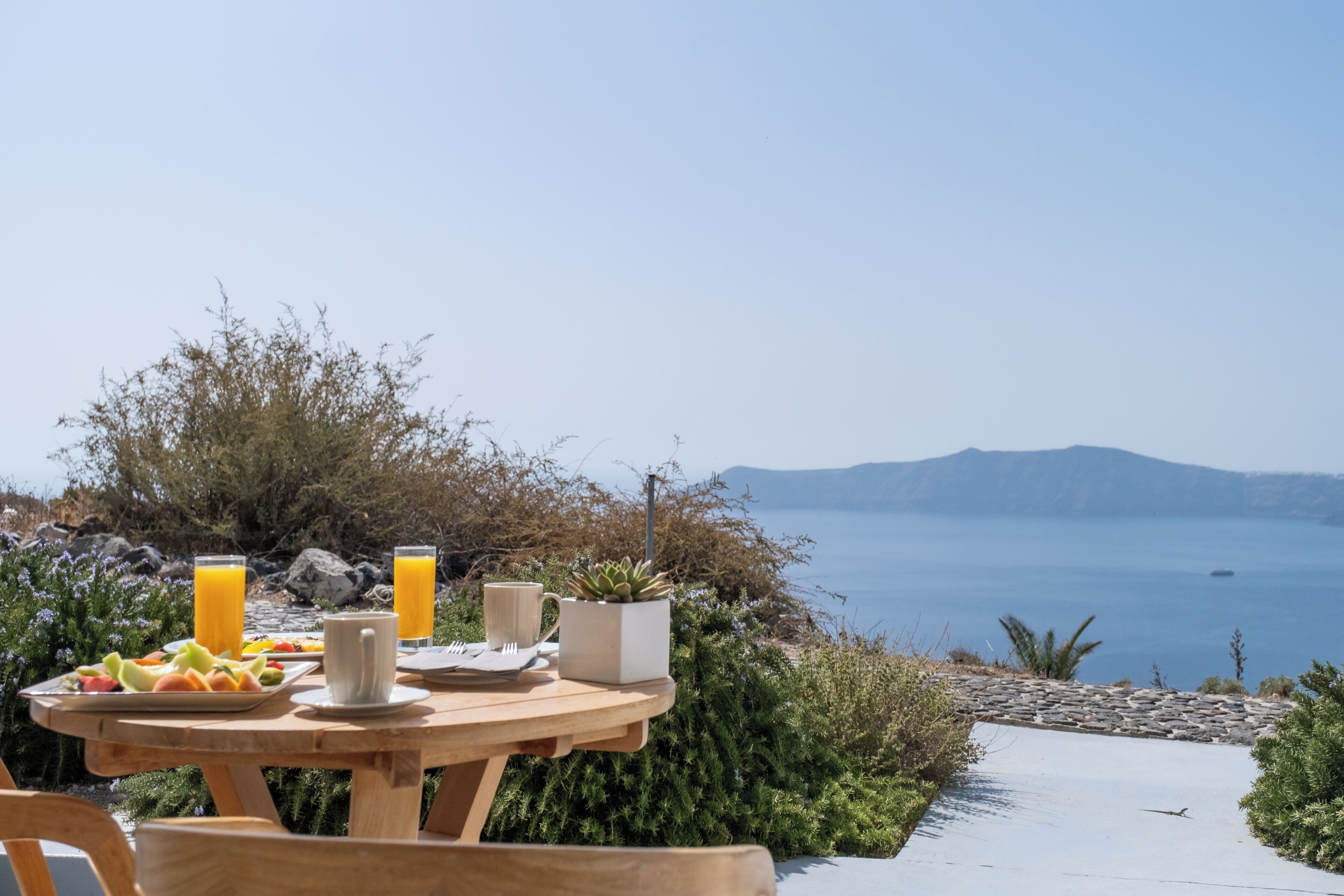 A table set outdoors with a view of the sea and mountains.