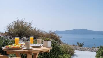 A table set outdoors with a view of the sea and mountains.