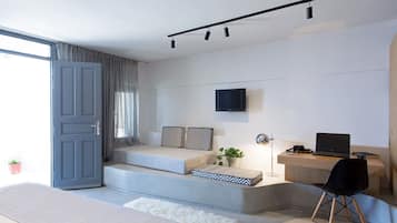 A modern living room with a sofa, a coffee table, a TV mounted on the wall, and a laptop on a desk.