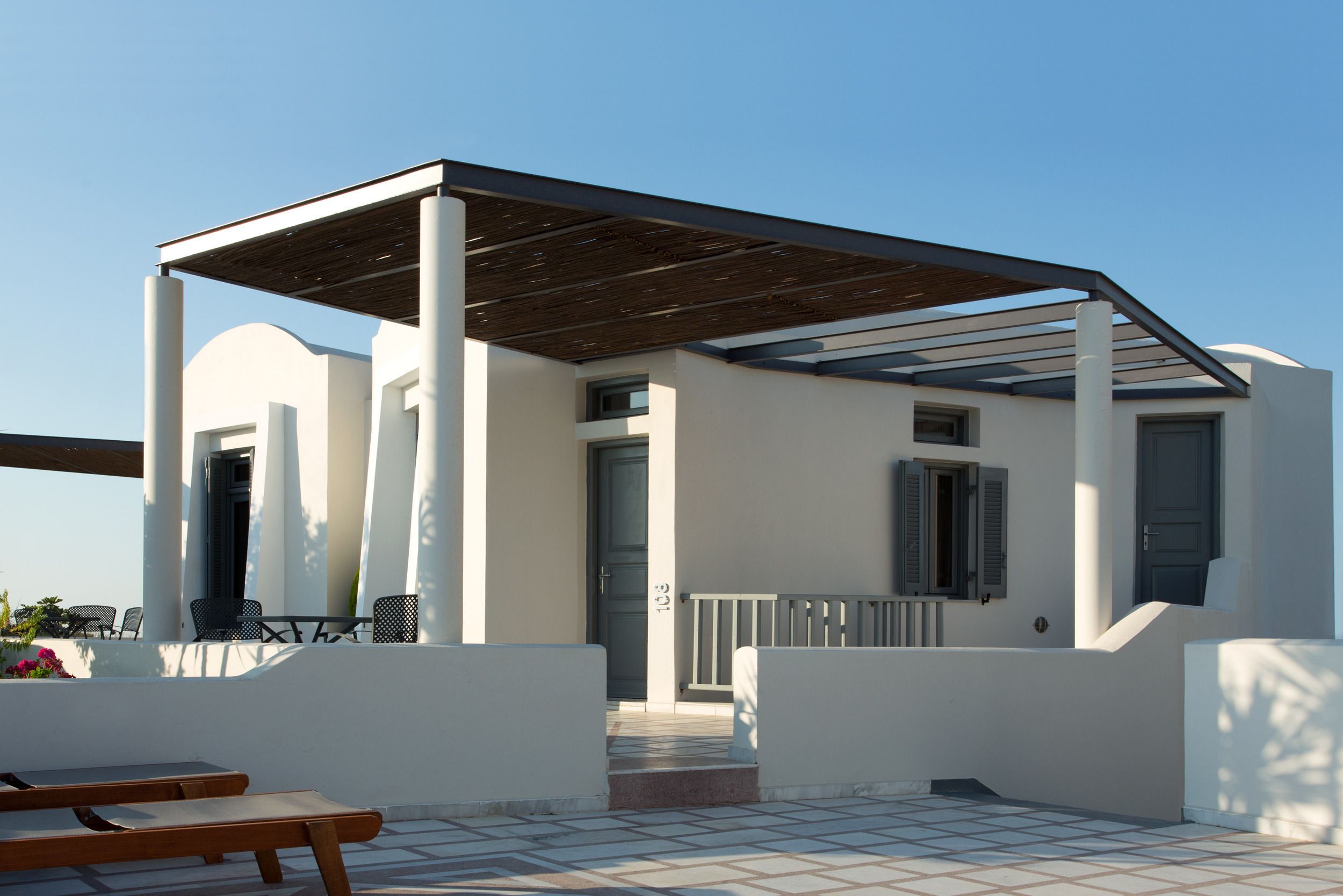 A modern building with a covered patio area, white walls, and a tiled floor.