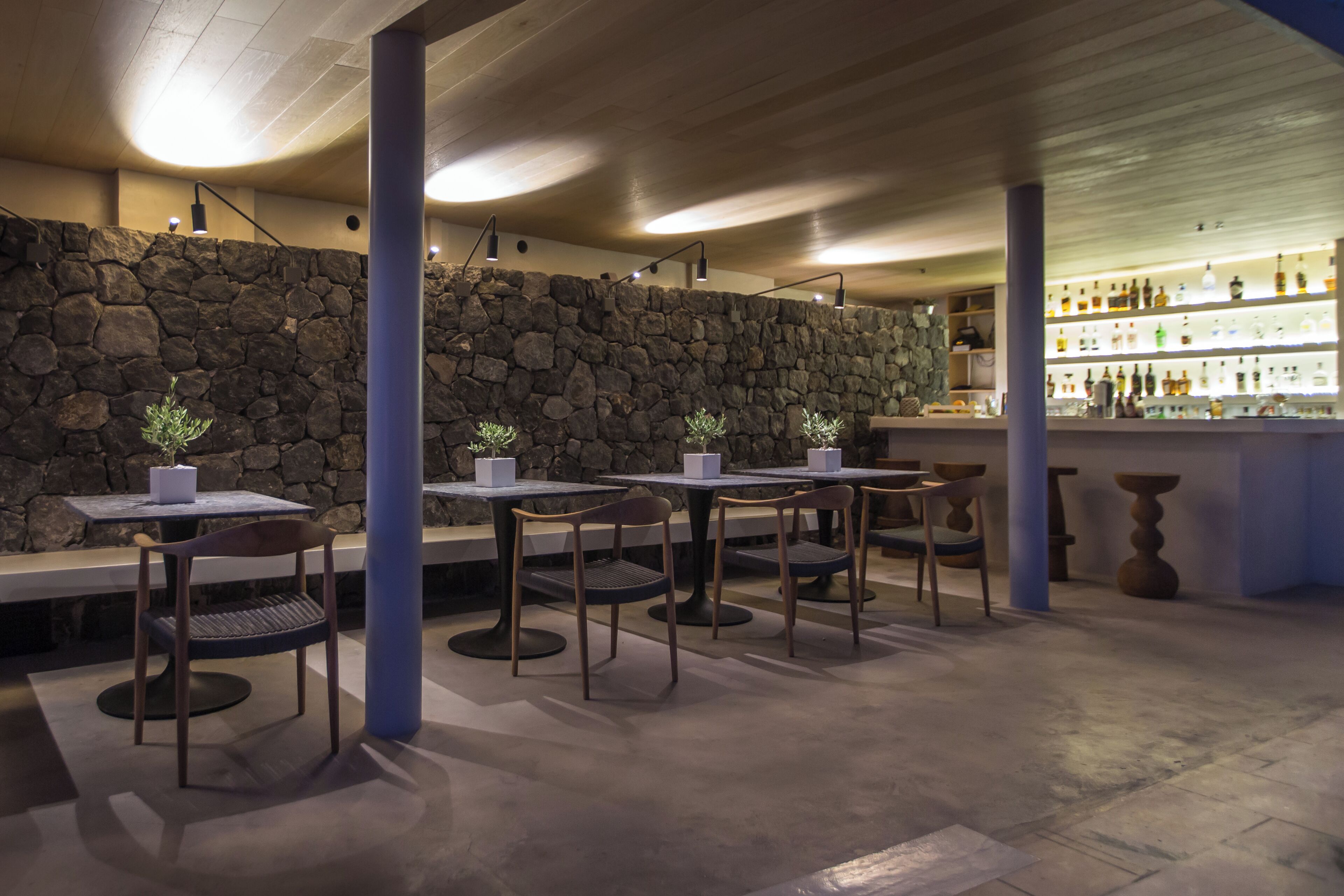 A restaurant interior with stone walls, tables, chairs, and a bar area.