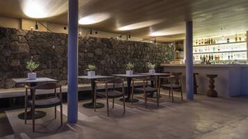 A restaurant interior with stone walls, tables, chairs, and a bar area.