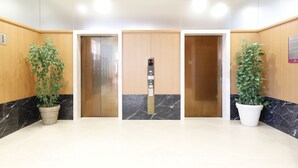 An elevator area with three doors, marble flooring, and potted plants.