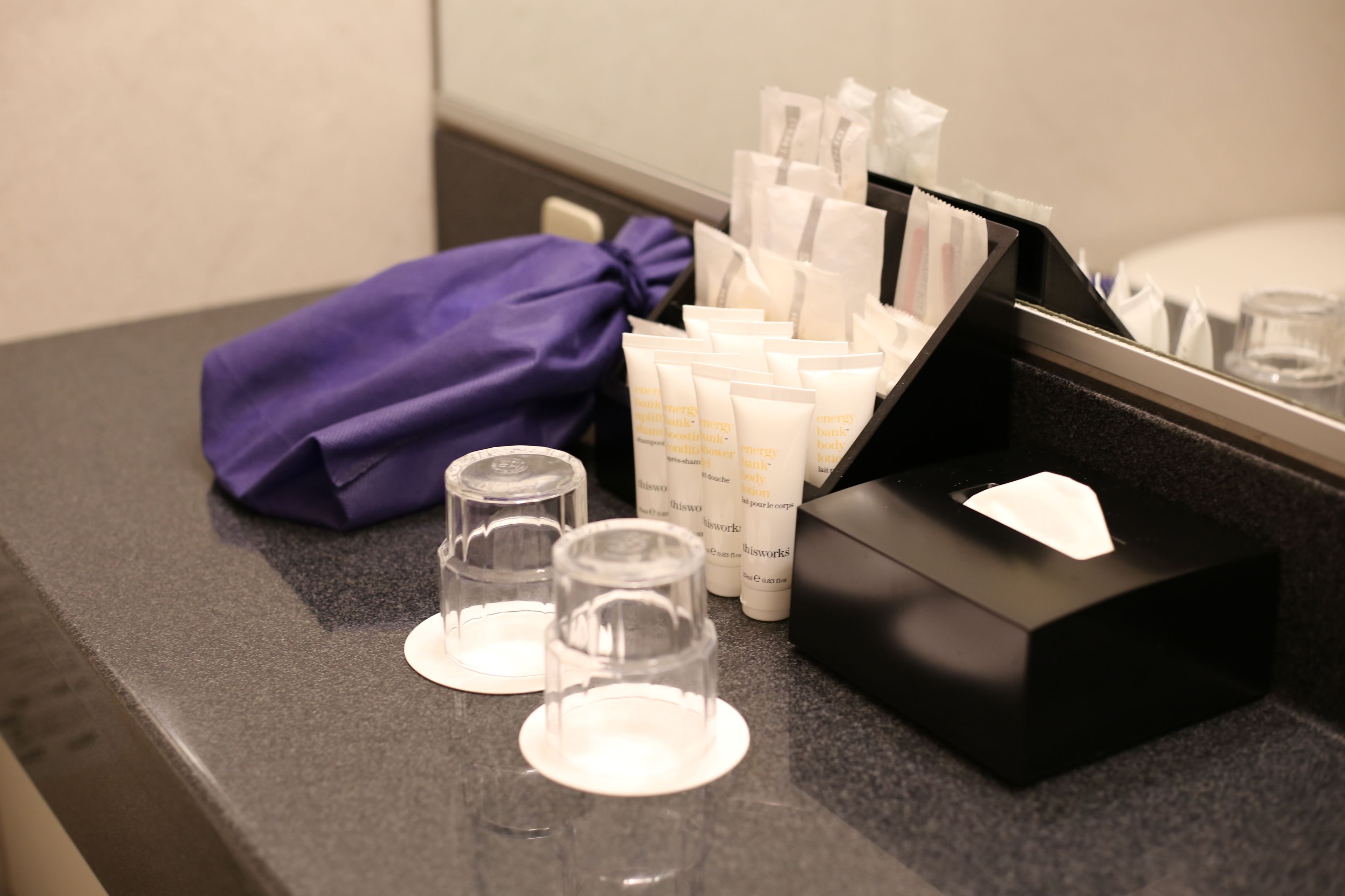 A bathroom counter with toiletries, a purple towel, and a tissue box.