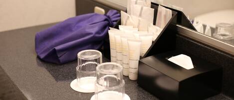 A bathroom counter with toiletries, a purple towel, and a tissue box.