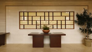 A reception area with a reception desk, a potted plant, and a decorative wall panel.