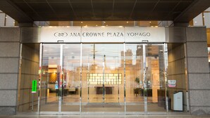 The entrance to ANA Crowne Plaza Yonago with a clear glass facade and a sign above the doors.