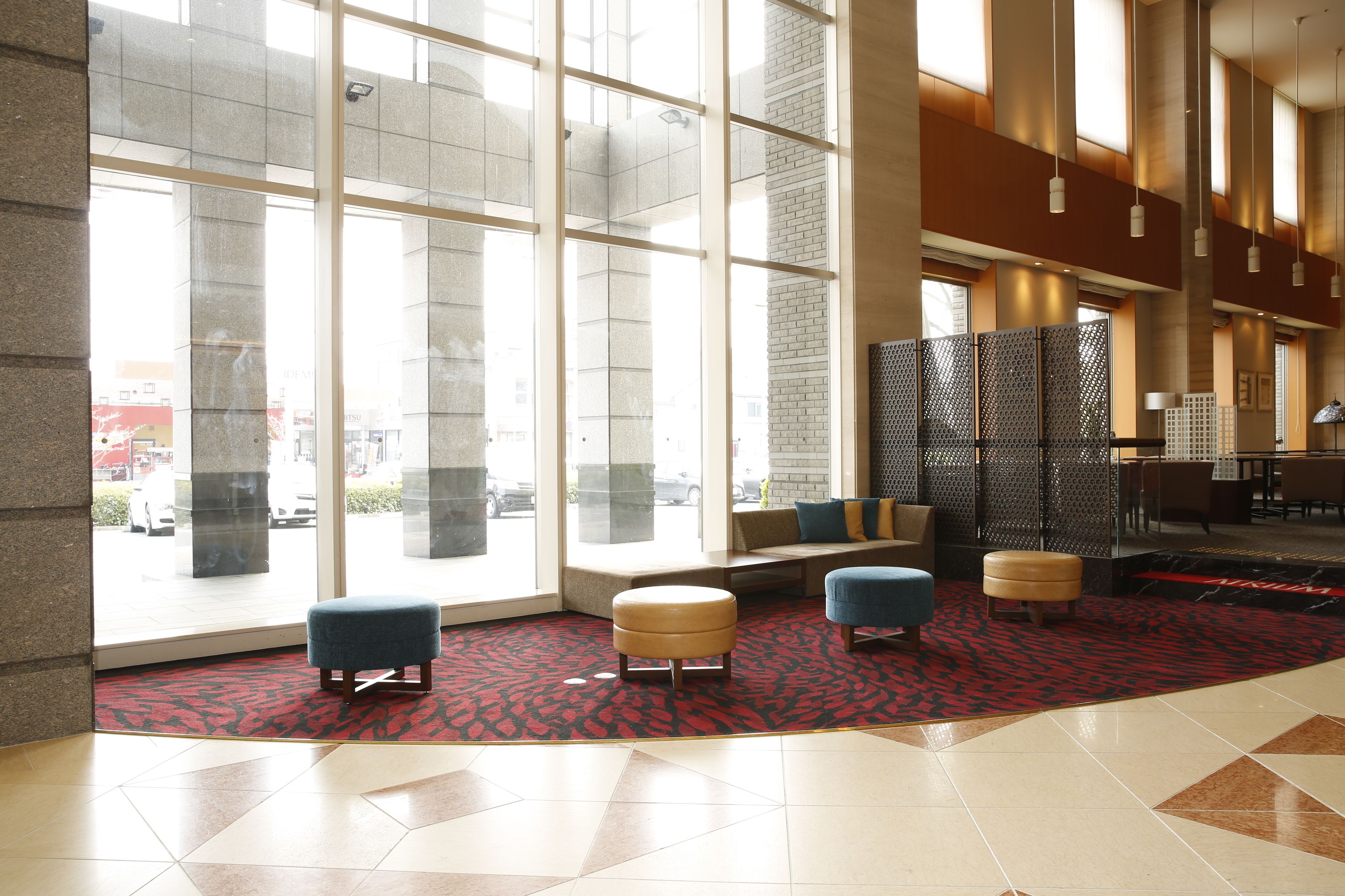A spacious lobby with large windows, seating areas, and a patterned carpet.