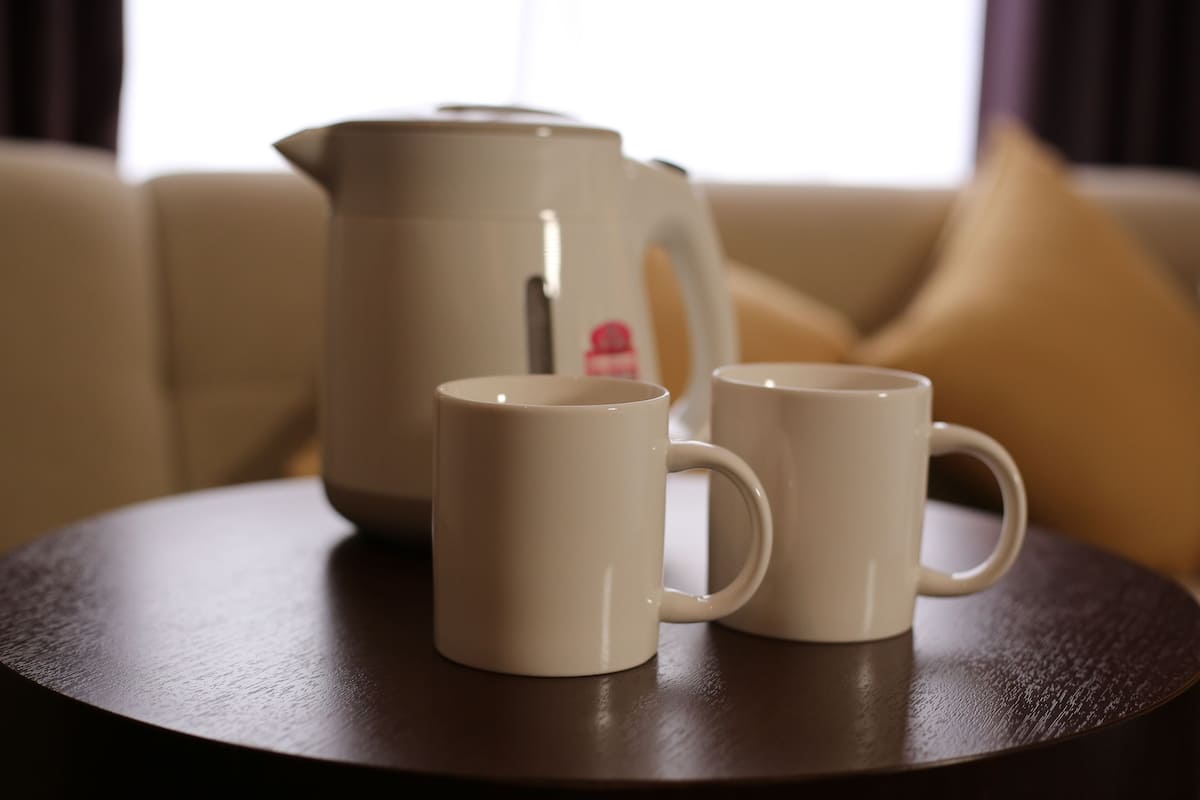 Deux tasses blanches sont posées sur une table ronde, et une cafetière beige se trouve à l’arrière-plan.