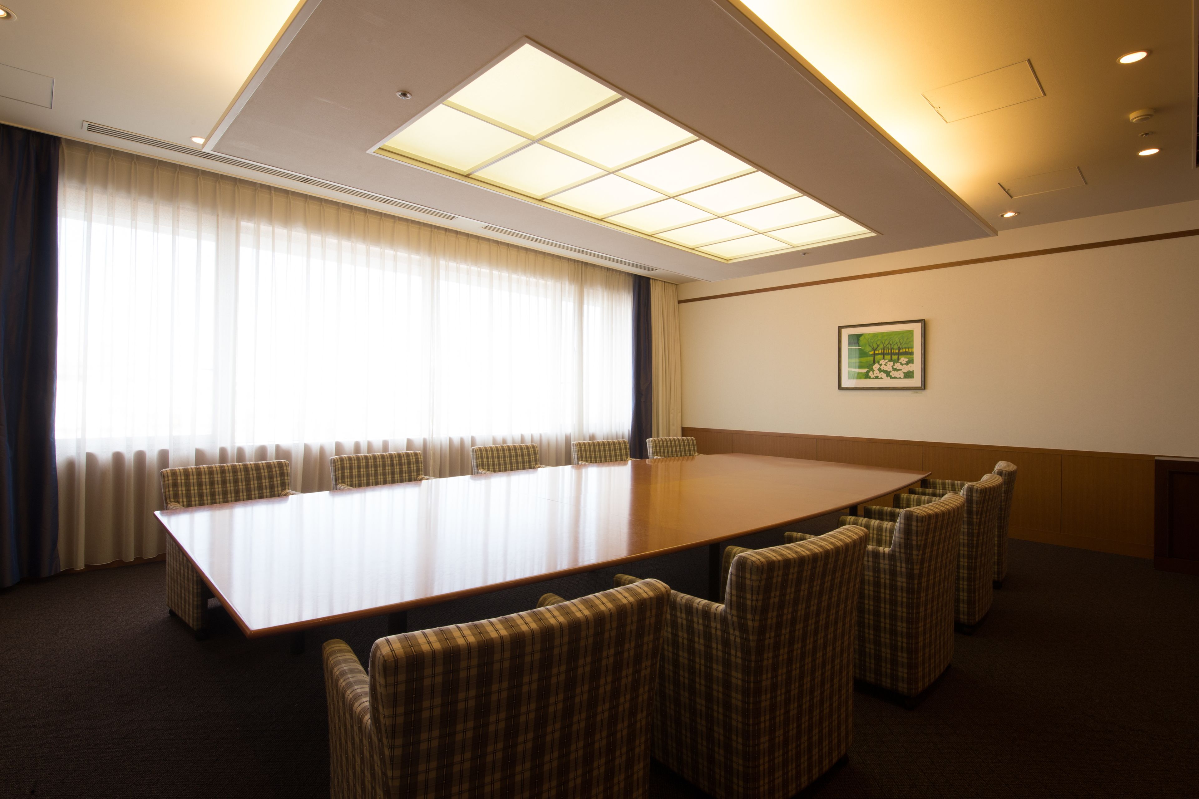 Uma sala de conferências com uma mesa comprida e seis cadeiras xadrez.