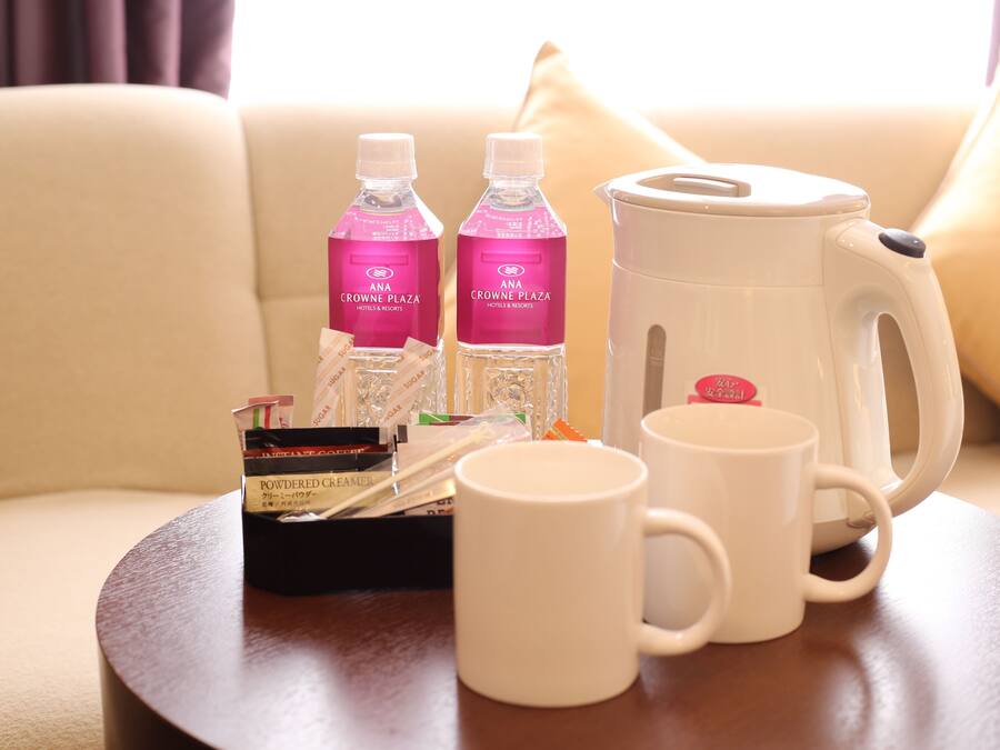 Een tafel met een koffiezetapparaat, twee waterflessen, een doosje melk en twee witte mokken.