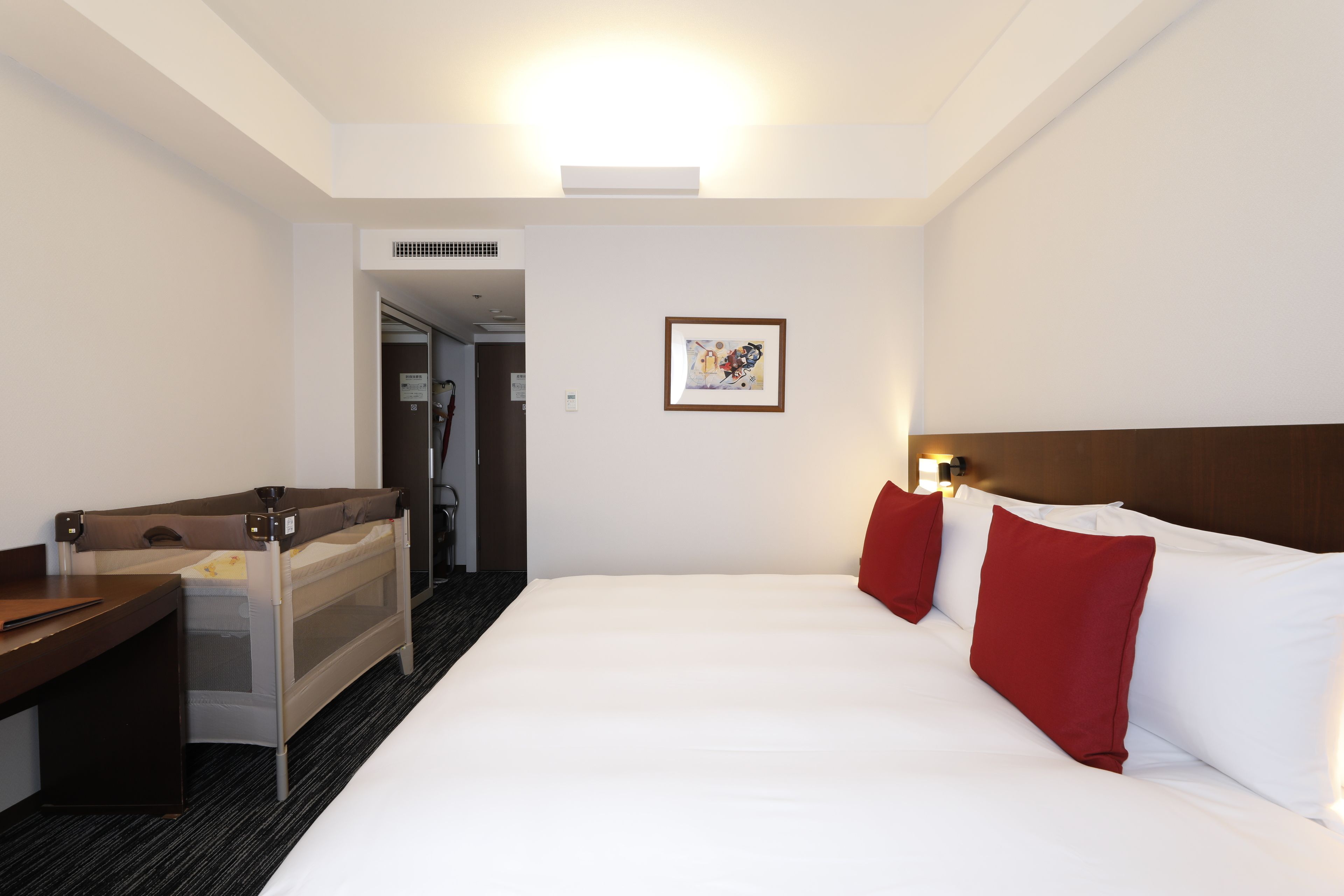 A hotel room with a bed, a desk, and a shower area.