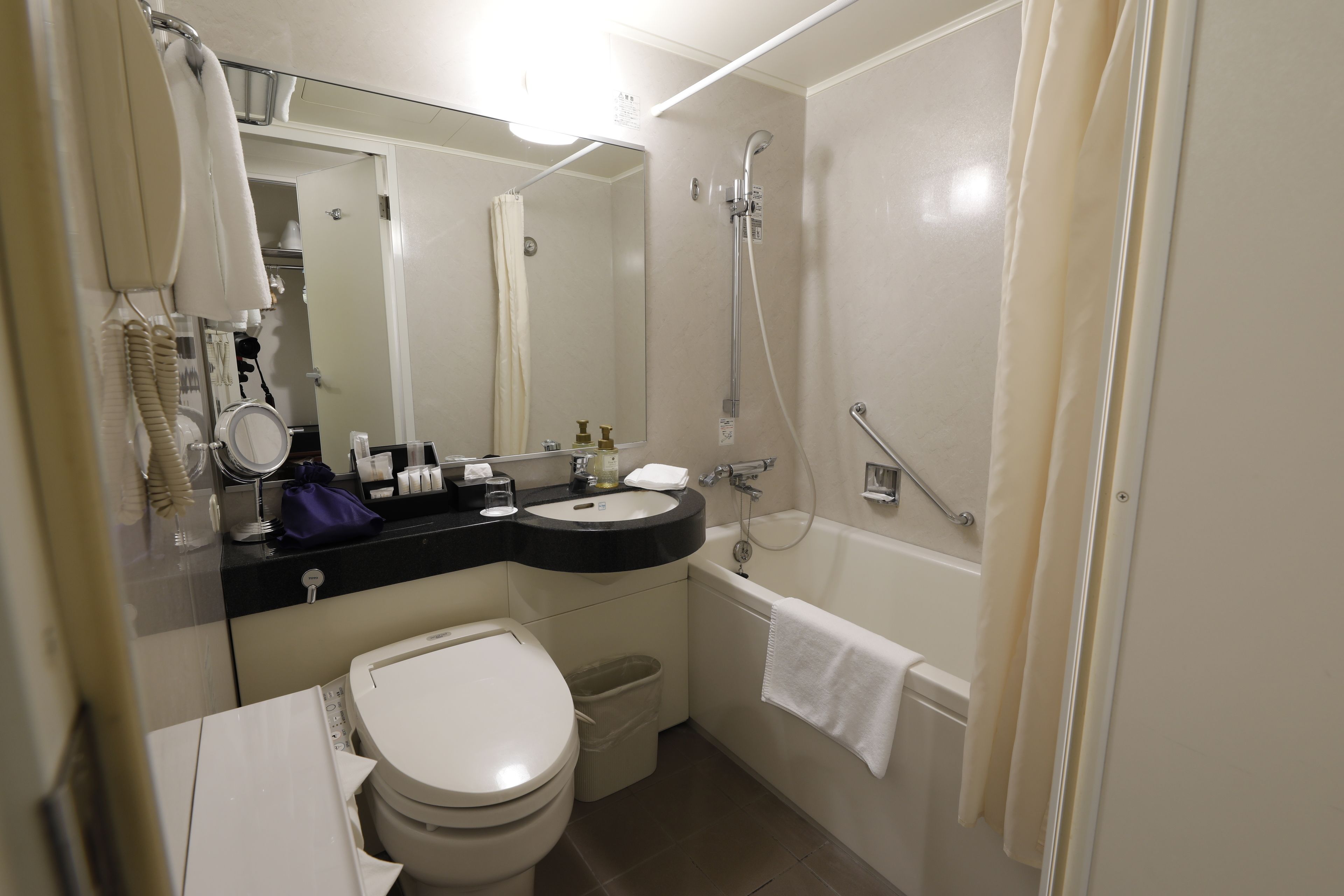 Een moderne badkamer met toilet, wastafel, spiegel en douche.