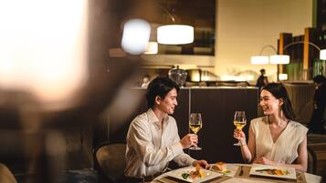 Una pareja cenando en una mesa en un restaurante con poca luz y un bar al fondo.