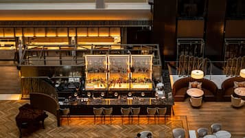 Un grand espace bar offrant de nombreuses options de sièges, notamment des tabourets de bar et des sièges rembourrés, et une cuisine ouverte visible au fond.