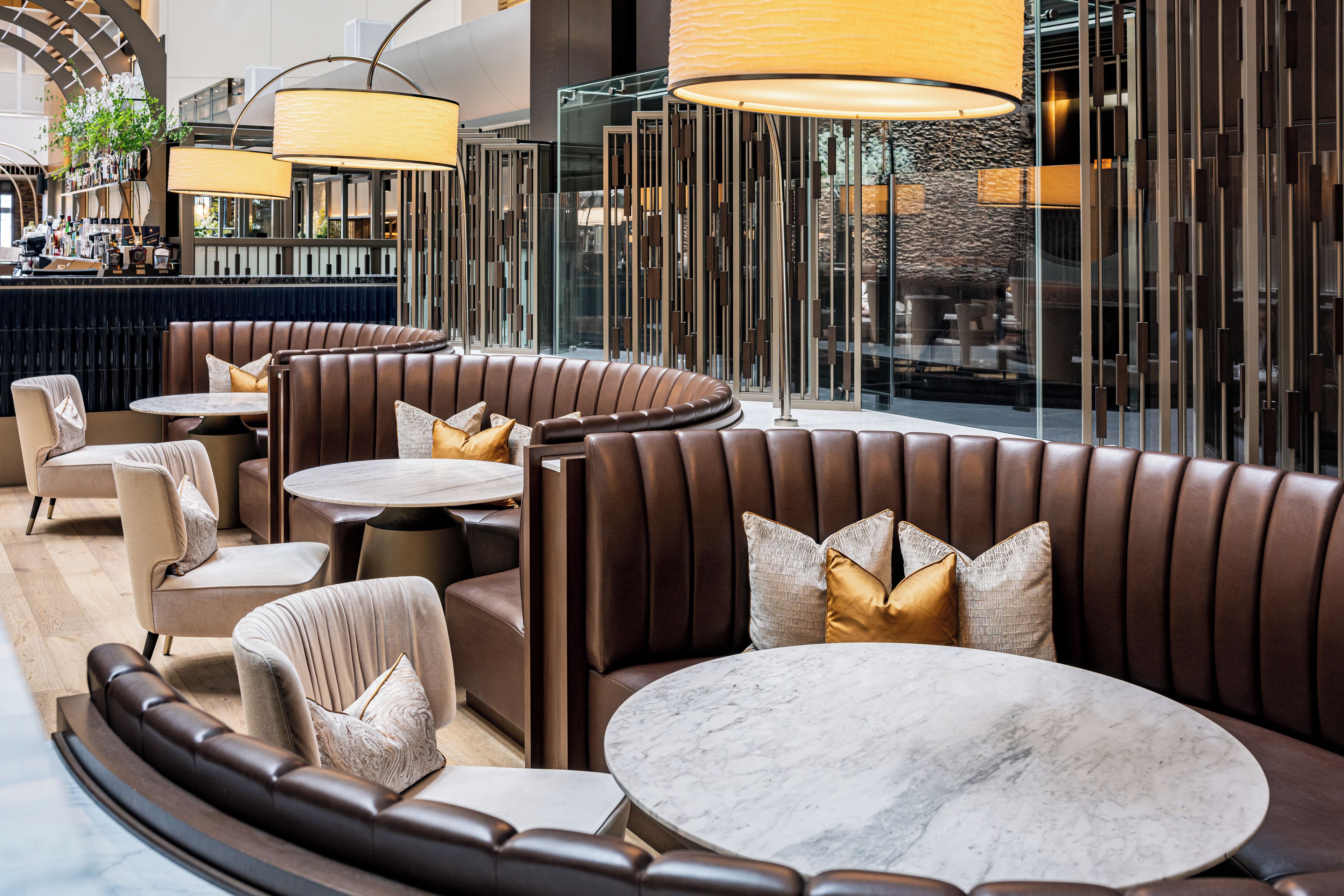 A modern lounge area with leather booths, marble tables, and ambient lighting.