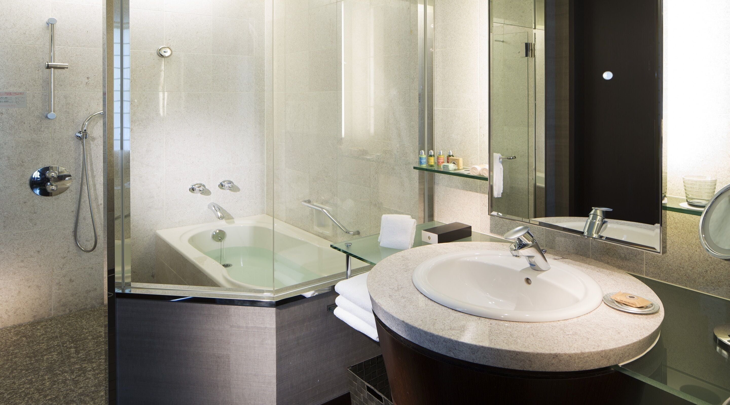 A modern bathroom with a glass-enclosed shower, a freestanding bathtub, and a round vanity with a sink.