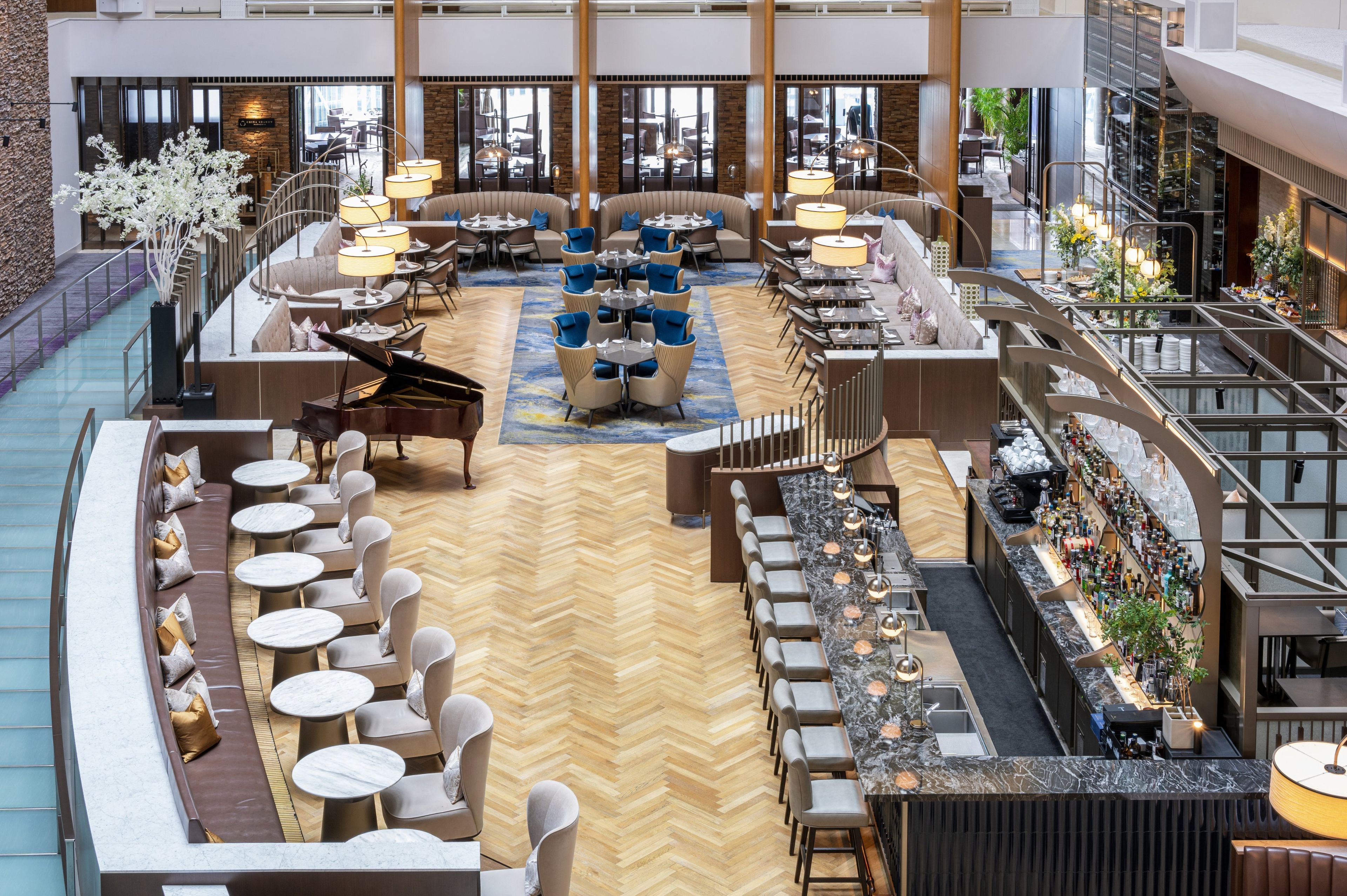 A spacious hotel lobby with a central seating area, a piano, and a bar.
