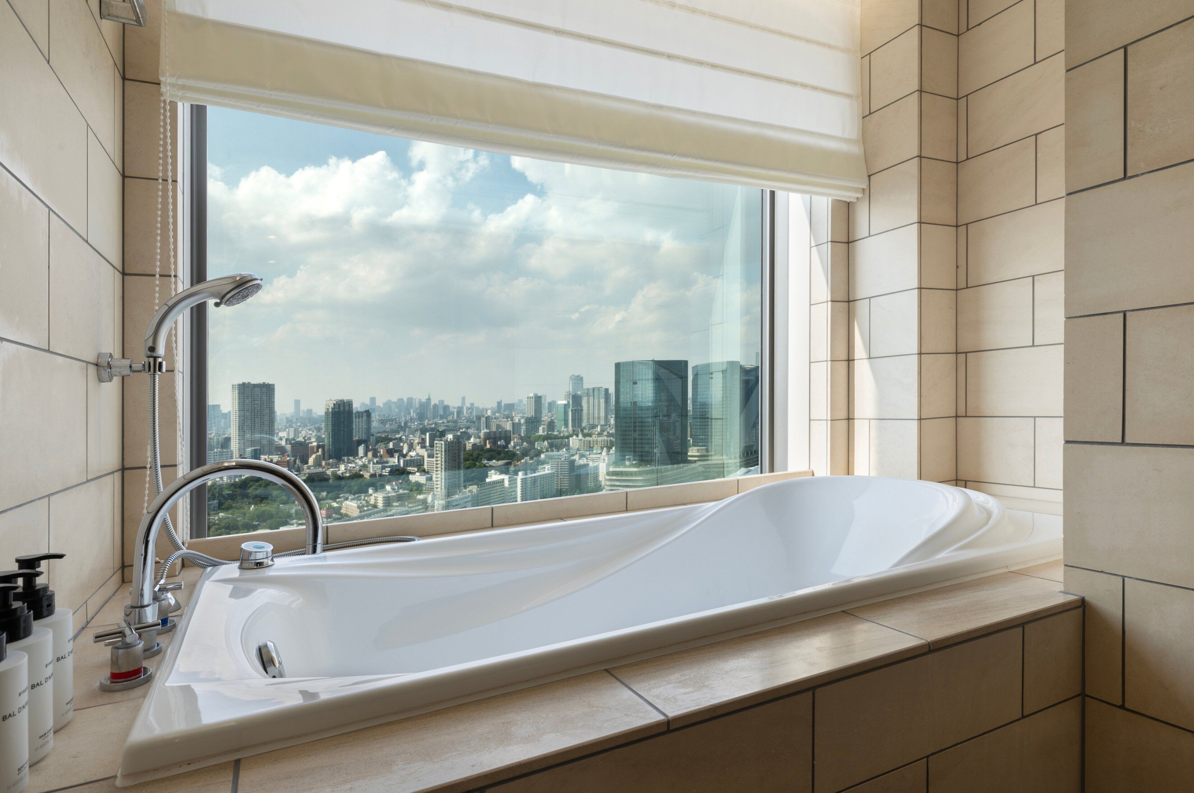 Ein modernes Badezimmer mit einer großen Badewanne, einem Fenster mit Stadtblick und einem Wasserhahn.