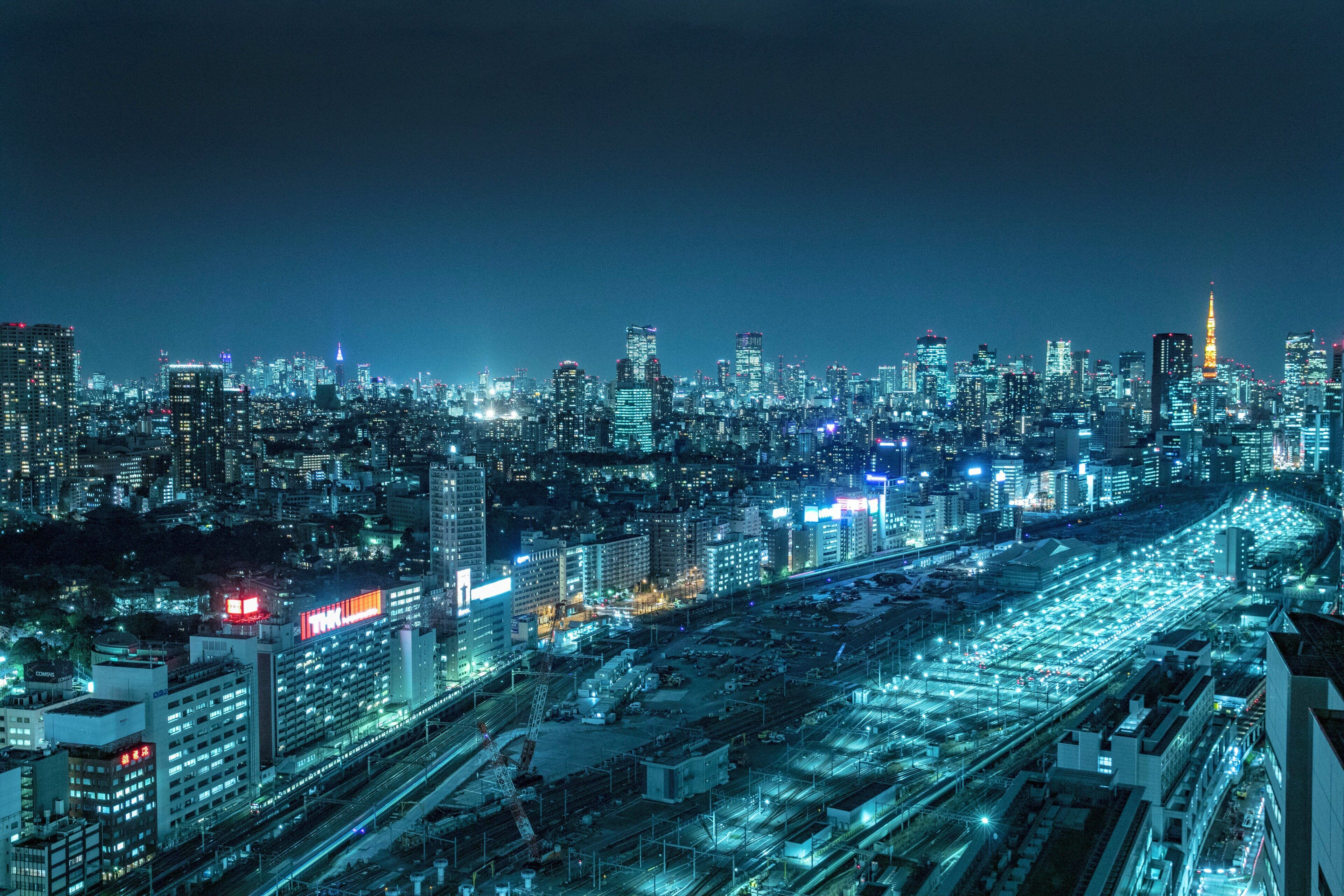 A nighttime cityscape with illuminated buildings and a busy highway.