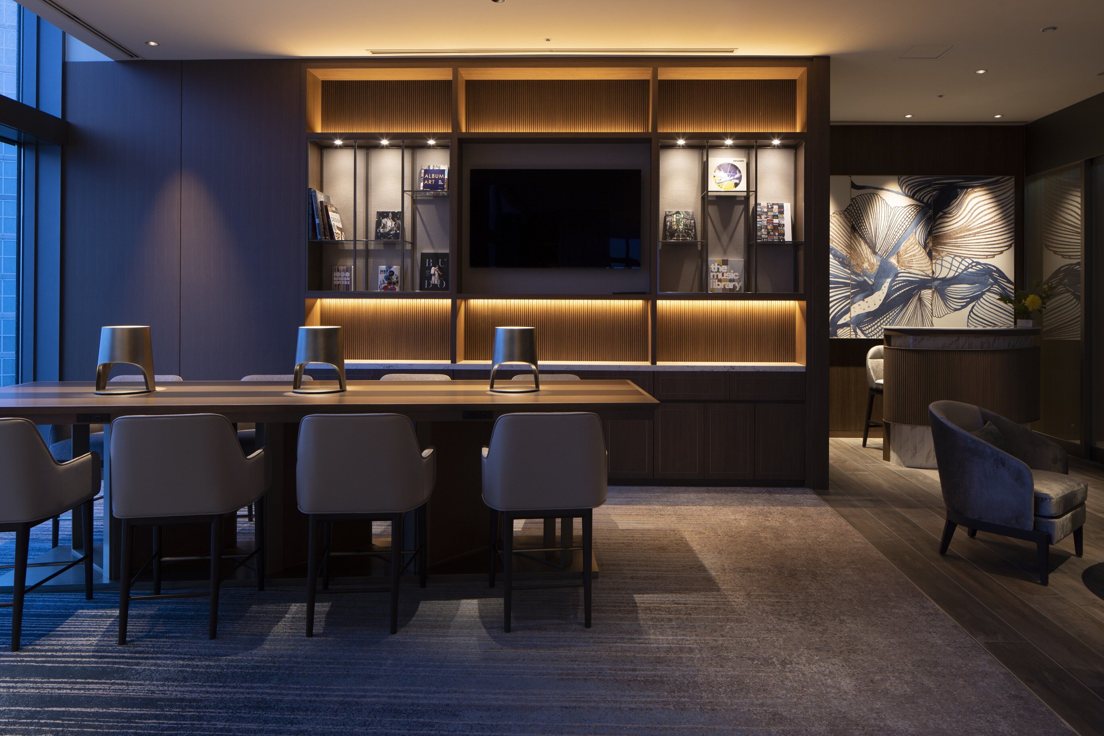 A modern interior with a dark wood finish, a large flat-screen TV, and a seating area with chairs and a table.
