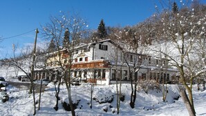 A large, multi-story building with a snow-covered roof and surrounding trees. - Hotel Conca Verde (Zone)