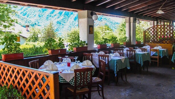 An outdoor restaurant with tables set for dining, surrounded by wooden lattice panels and potted plants. - Hotel Conca Verde (Zone)
