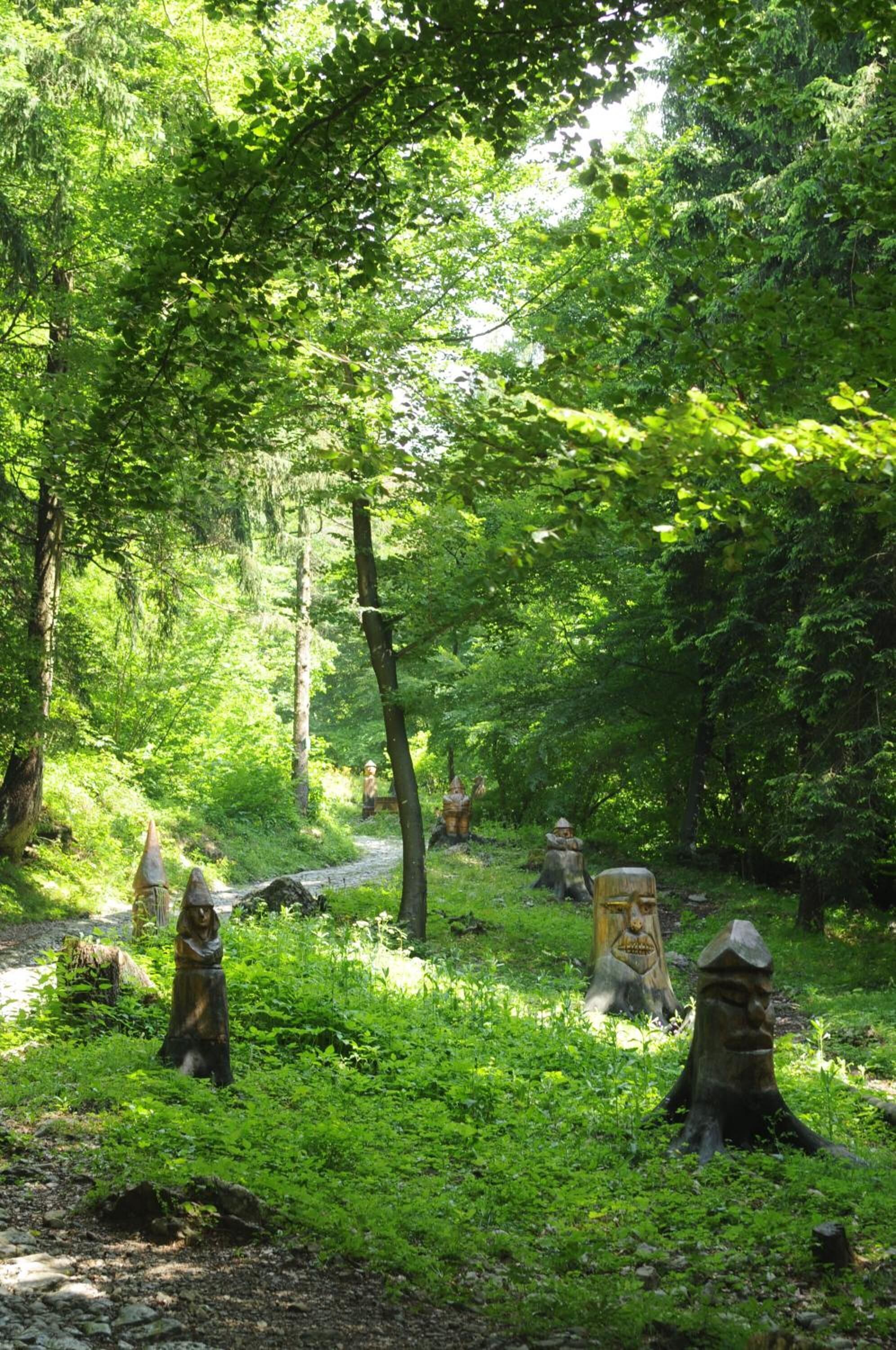 Une zone boisée agrémentée de sculptures et d’un sentier en pierre.