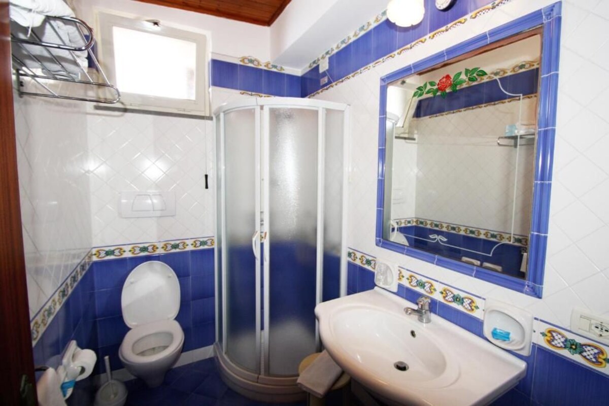 A bathroom with a toilet, a shower enclosure, and a sink.