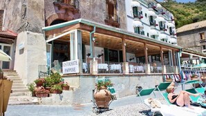 Un immeuble abritant au rez-de-chaussée un restaurant appelé « Ristorante Paopone », doté d’une terrasse et de places assises en plein air.