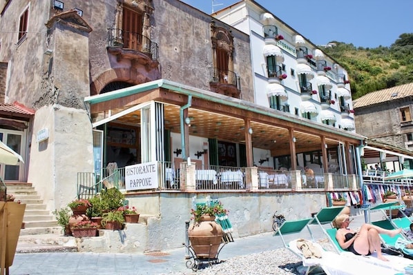 Un edificio con restaurante llamado "Ristorante Paopone" en la planta baja, que cuenta con mesas al aire libre y una terraza.