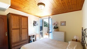 Une chambre avec un plafond en bois, un lit, une armoire, un bureau et un téléviseur.