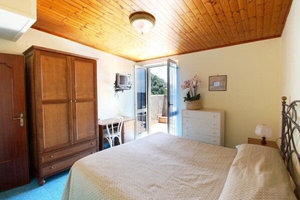 A bedroom with a wooden ceiling, a bed, a wardrobe, a desk, and a television. - Hotel La Certosa (Massa Lubrense)