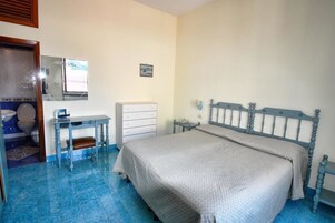Un dormitorio con cama, escritorio, cómoda y espejo.