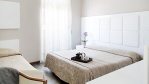 A hotel room with a large bed, a bedside table with a vase of flowers, and a chair. - Hotel Primavera (Stresa)