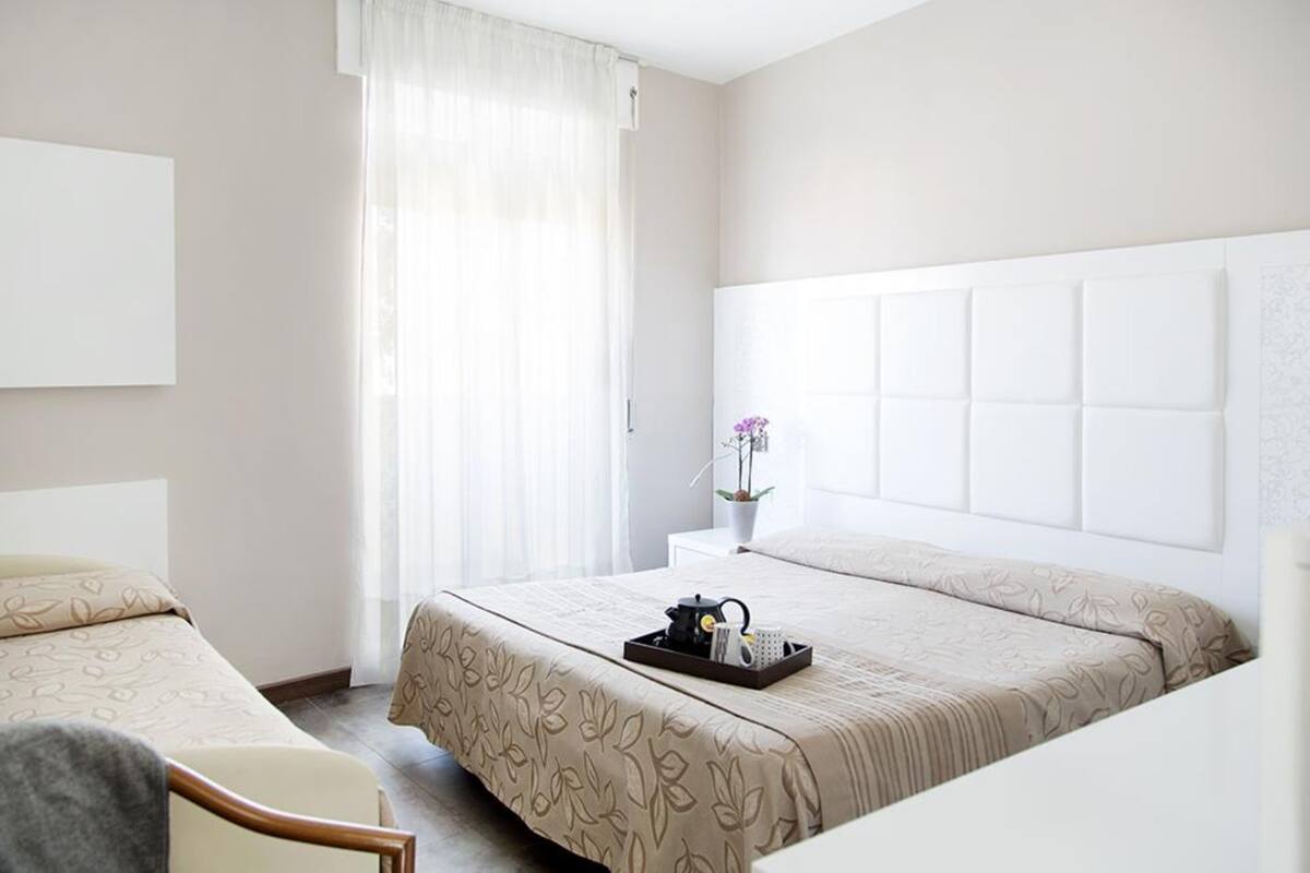 Una habitación de hotel con una cama grande, una mesita de noche con un jarrón de flores y una silla.
