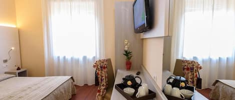 A hotel room with two beds, a desk with a mirror, a television, and a window with curtains.